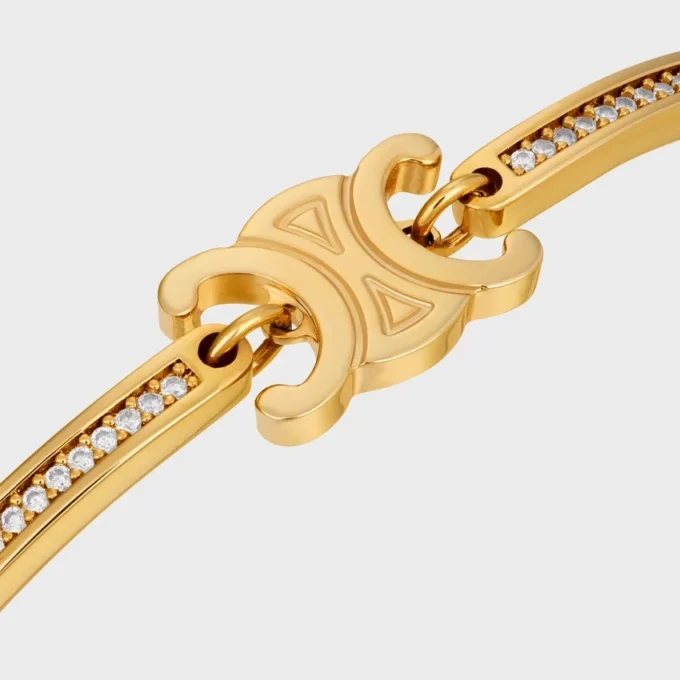 Triomphe scharnierende glinsterende armband van strass en messing met gouden afwerking